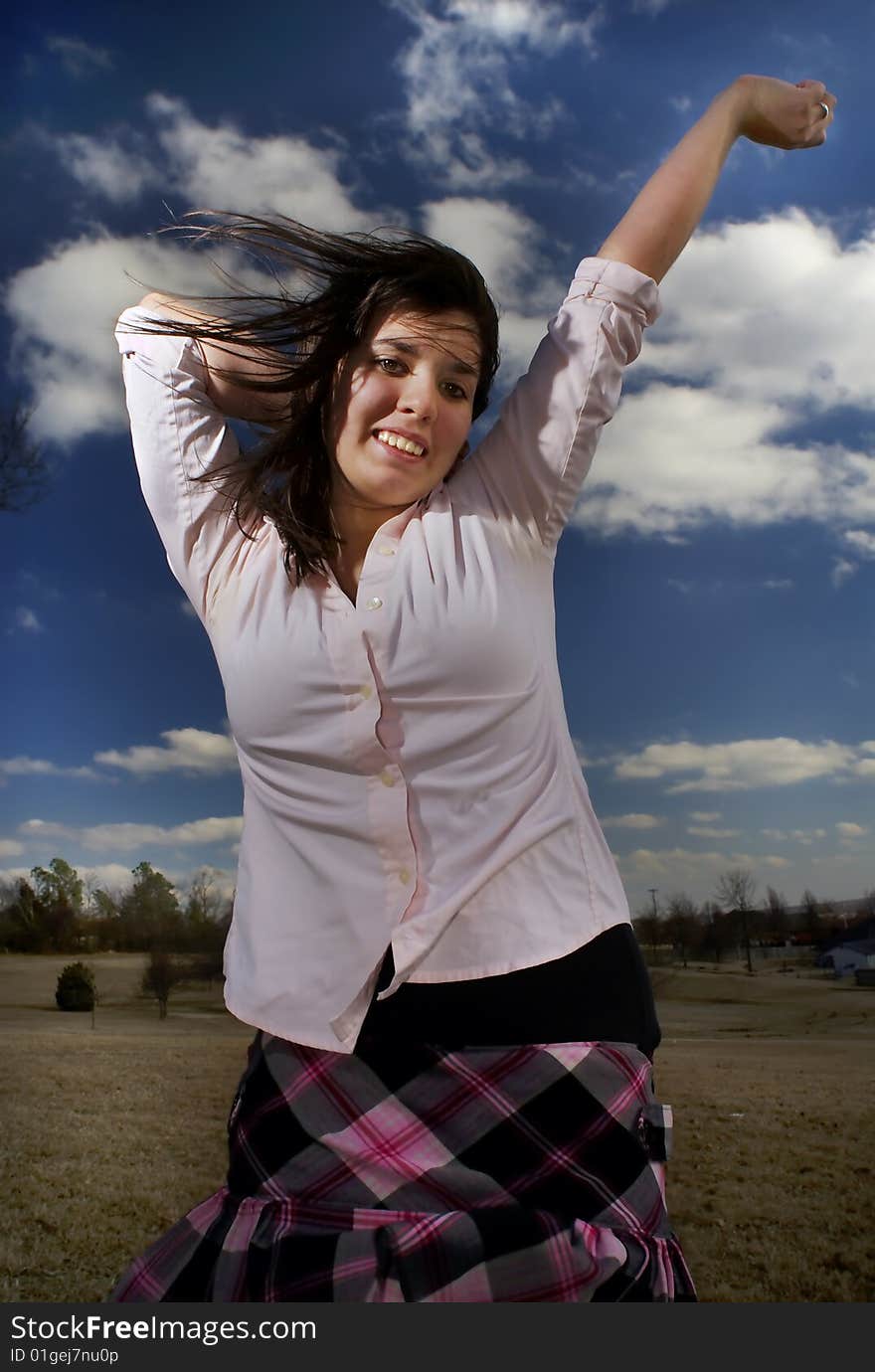 A teen expresses her exuberance against a brilliant sky. A teen expresses her exuberance against a brilliant sky.