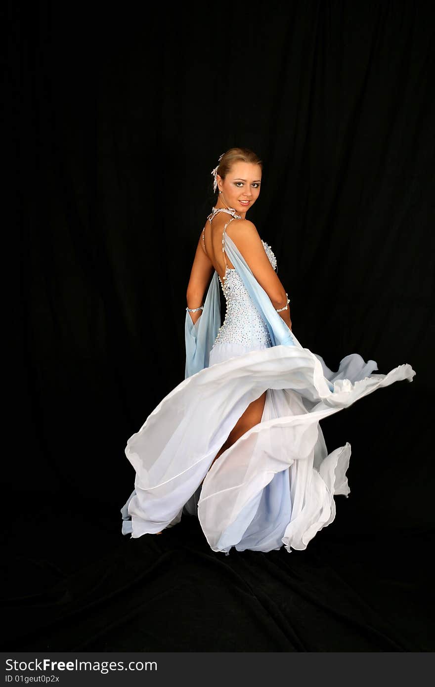 Dancer in classical blue-white dress against black background