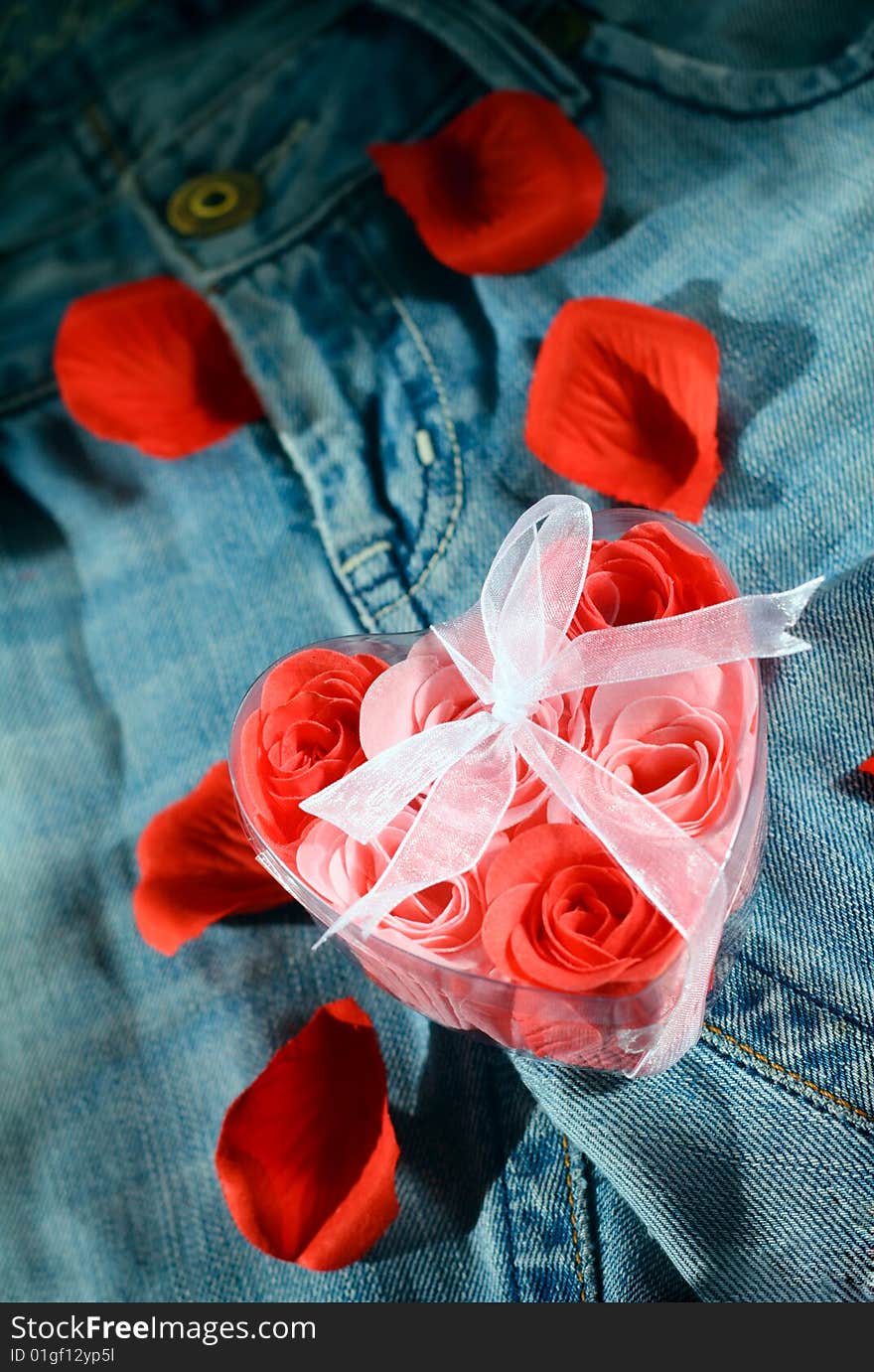 Roses in a gift box in shape of heart on jeans fabric. Roses in a gift box in shape of heart on jeans fabric