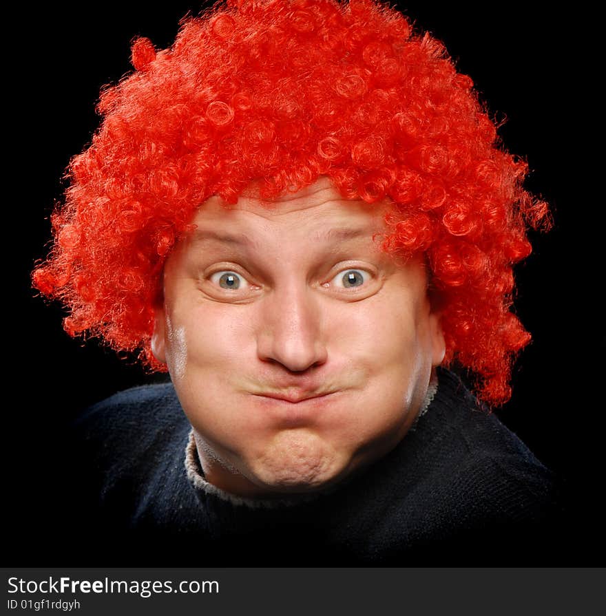 Close up shot of a man in clown's wig having fun, making faces and showing his tongue, isolated on black background. Close up shot of a man in clown's wig having fun, making faces and showing his tongue, isolated on black background