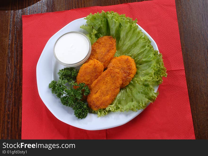 A plate of tastychops decorated with green salad and served with sauce. A plate of tastychops decorated with green salad and served with sauce