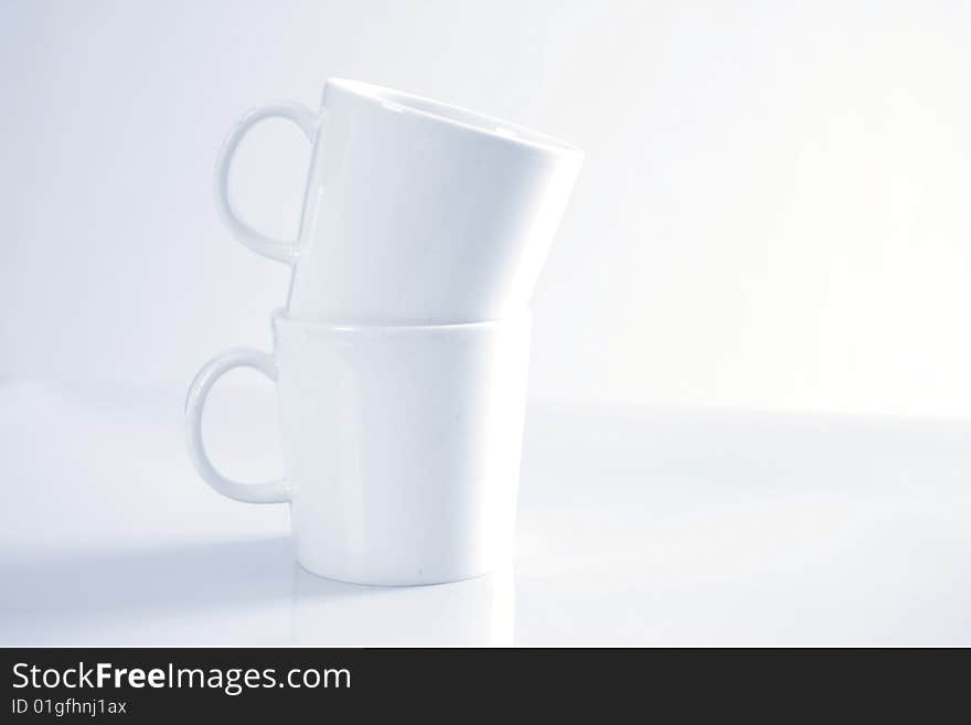 Two white porcelain mugs stacked on top of each other. Two white porcelain mugs stacked on top of each other