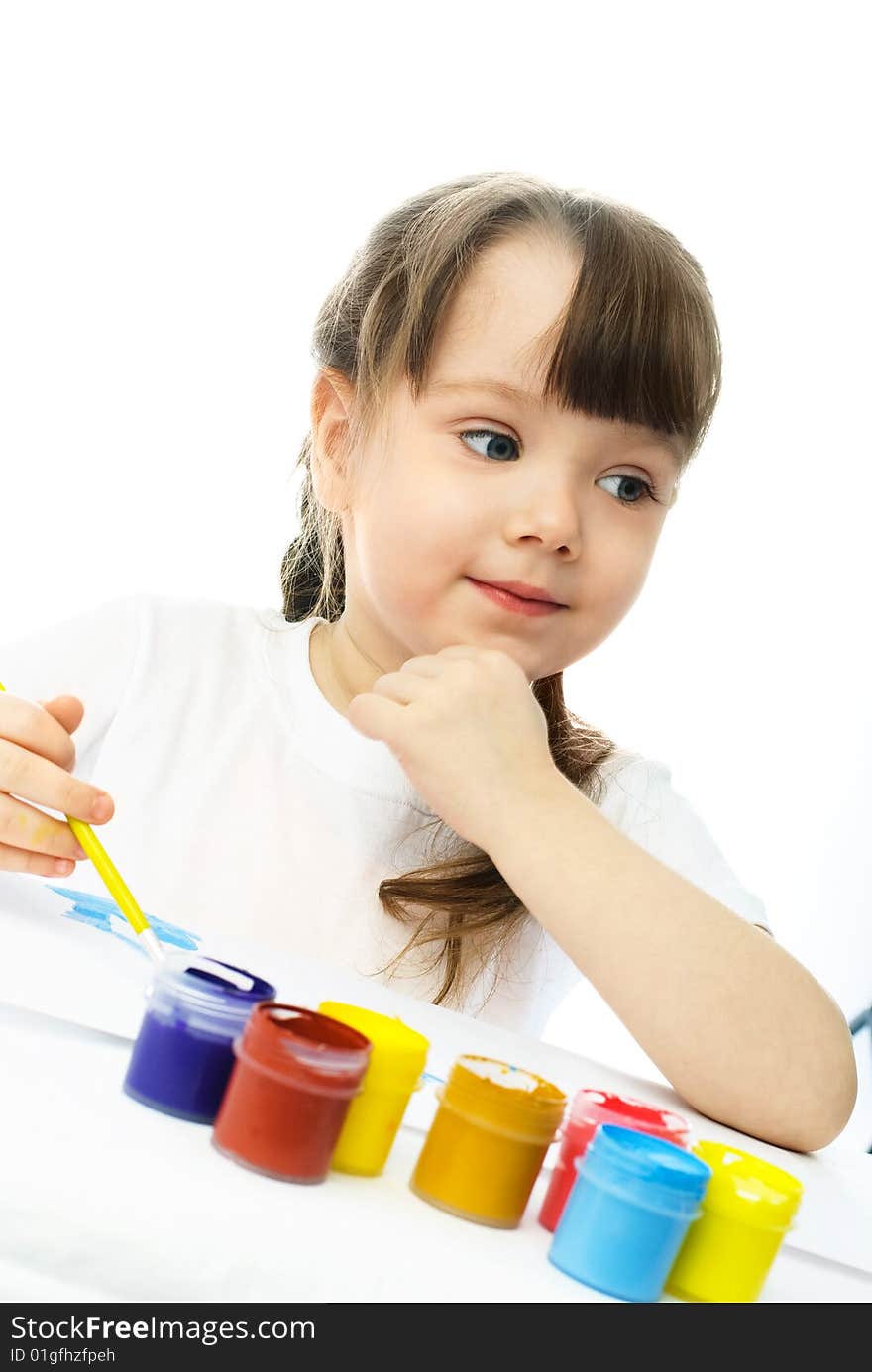 Cute dreamy little girl sitting by the table and painting with watercolor. Cute dreamy little girl sitting by the table and painting with watercolor