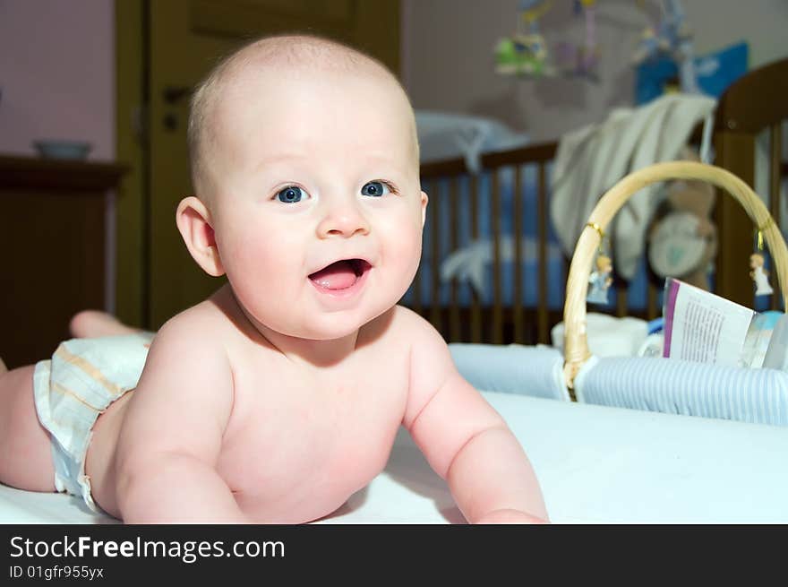 Four month smiling baby in diaper lying on bed on belly. Four month smiling baby in diaper lying on bed on belly.