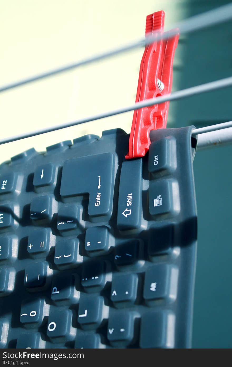 Flexible keyboard on clothesline with a red peg. Flexible keyboard on clothesline with a red peg
