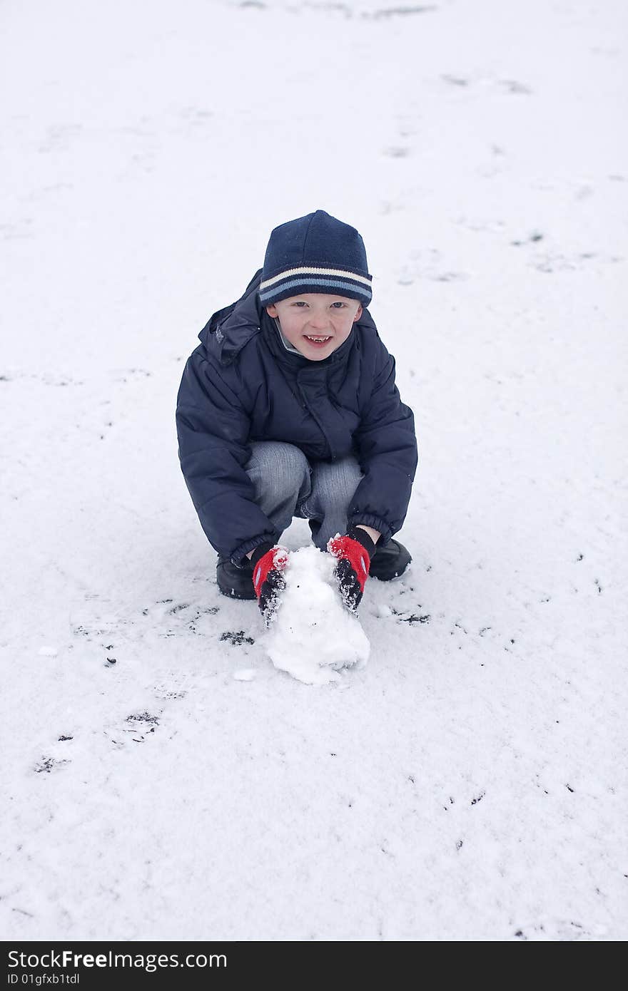 Child playing in the snow he is wearing hat and gloves. Child playing in the snow he is wearing hat and gloves