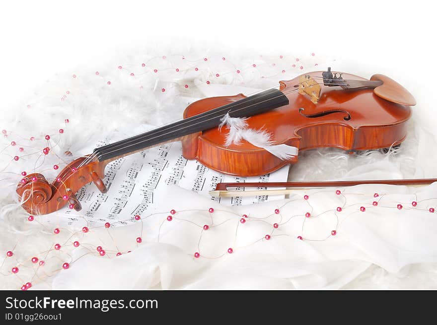 Violin and notes on white silk background with boa and furs