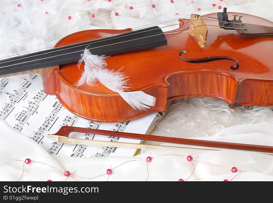 Violin and notes on white silk background with boa and furs