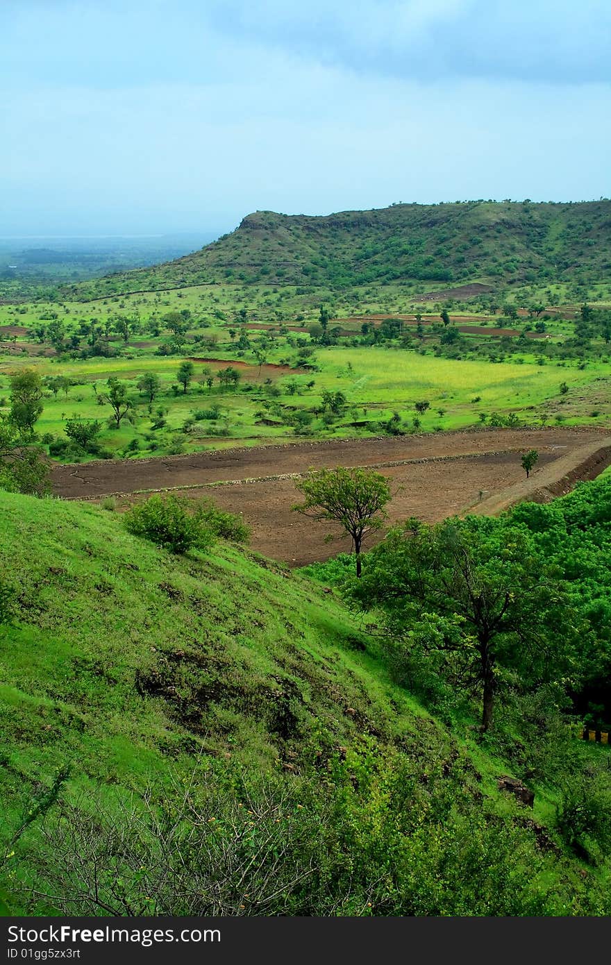 A beautiful landscape scene with vibrant green fields and distant mountain. A beautiful landscape scene with vibrant green fields and distant mountain.