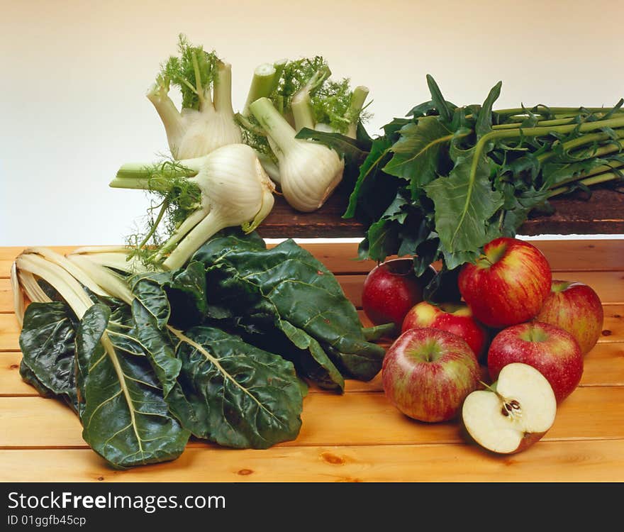 Vegetables and apples on a table made of wood