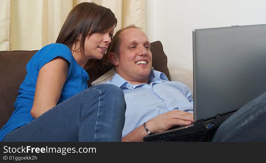 Young couple on the couch at home looking at the laptop!. Young couple on the couch at home looking at the laptop!