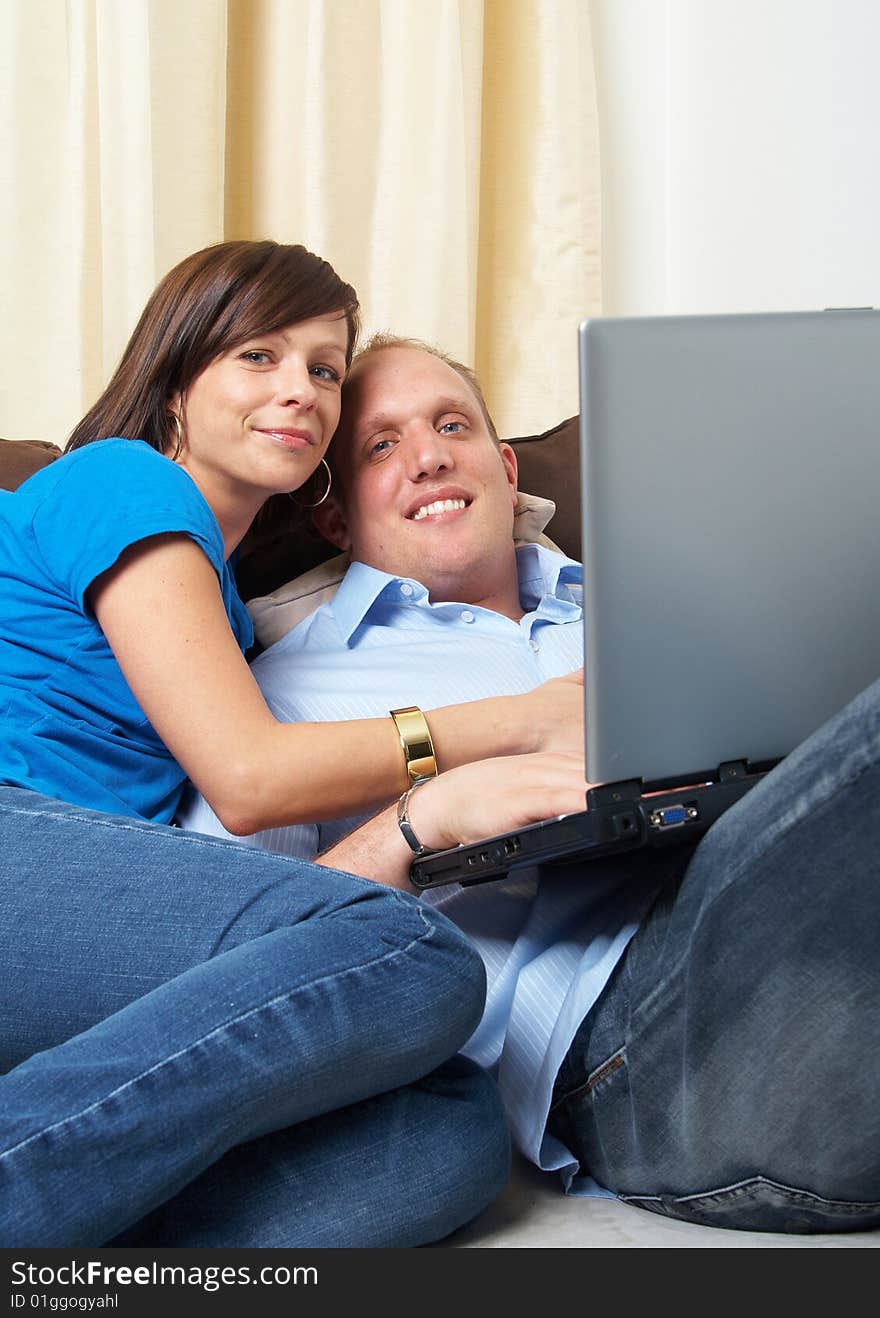 Young couple on the couch at home looking at the laptop!. Young couple on the couch at home looking at the laptop!