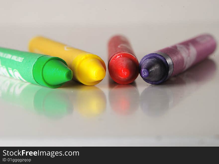 Crayons in different colors lying on a shiny desk. Crayons in different colors lying on a shiny desk