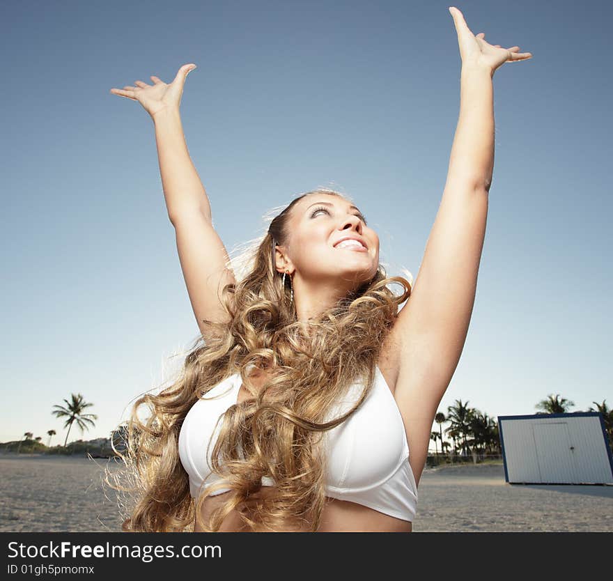 Beautiful woman extending her arms upward with the sun in the background. Beautiful woman extending her arms upward with the sun in the background