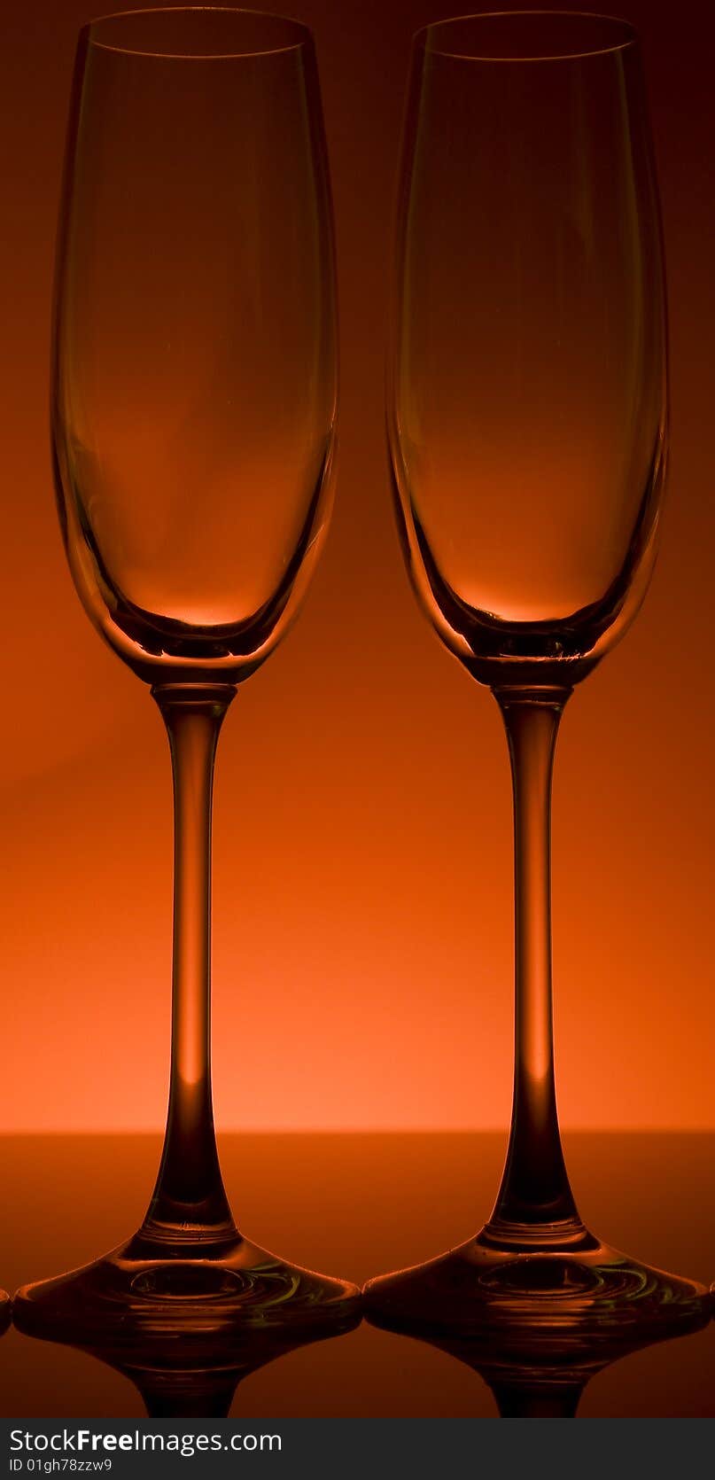 Wine and champagne glasses backlit in front of a red wall