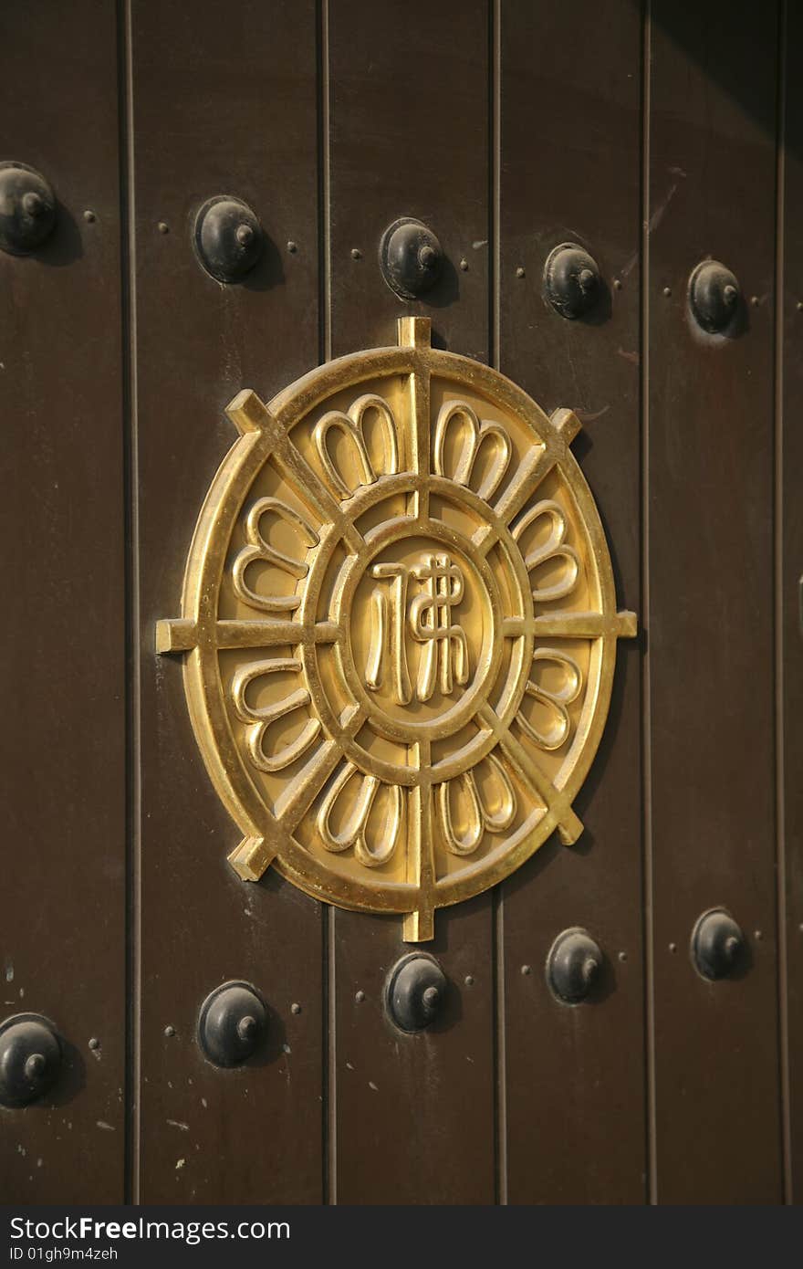 Buddhist Eight pointed Wheel Crafted in Gold and Set into brown Hardwood door with Iron rivets