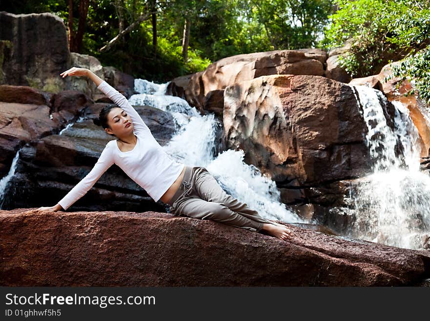 Outdoor waterfall young woman stretching her body. Outdoor waterfall young woman stretching her body