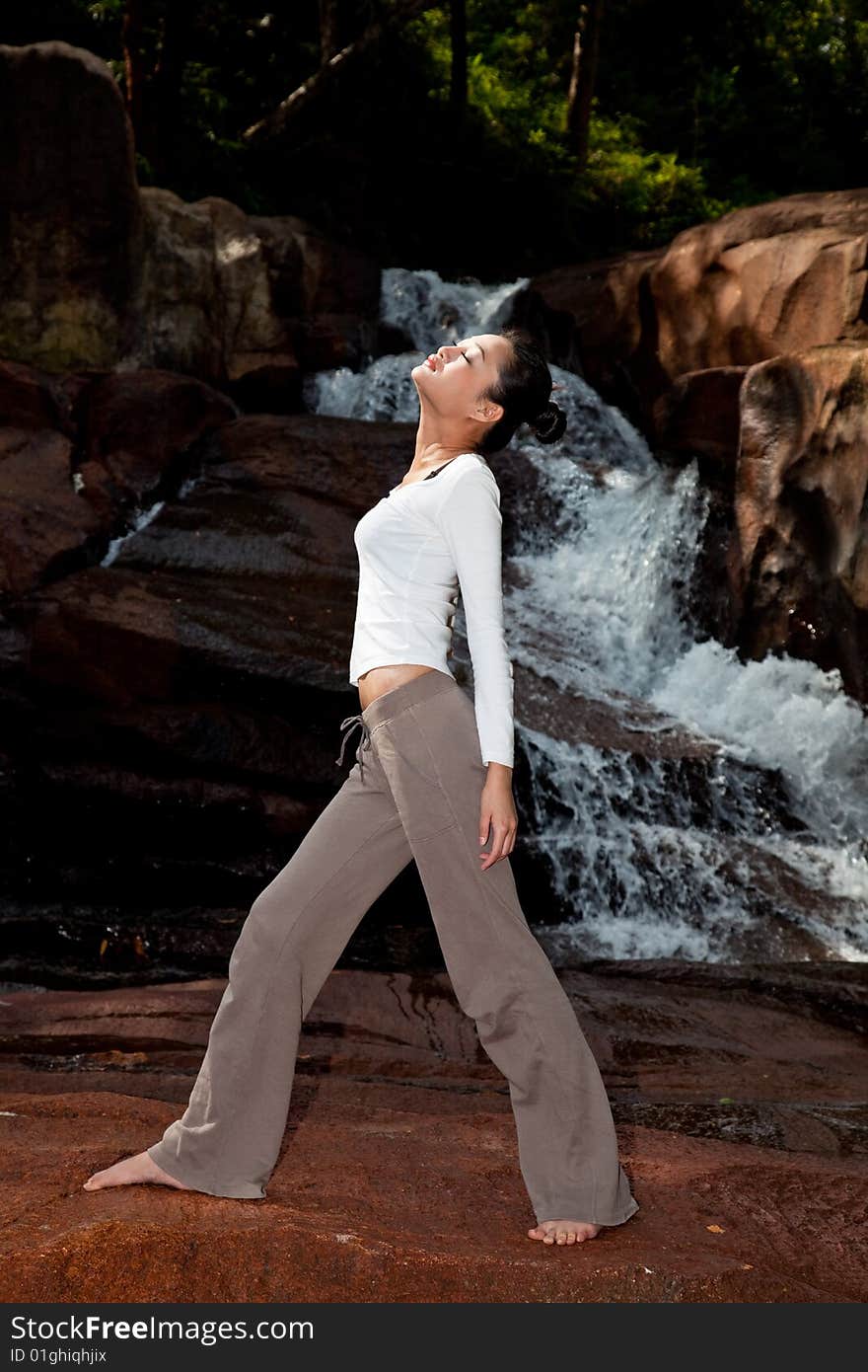 Outdoor waterfall young woman stretching her body. Outdoor waterfall young woman stretching her body