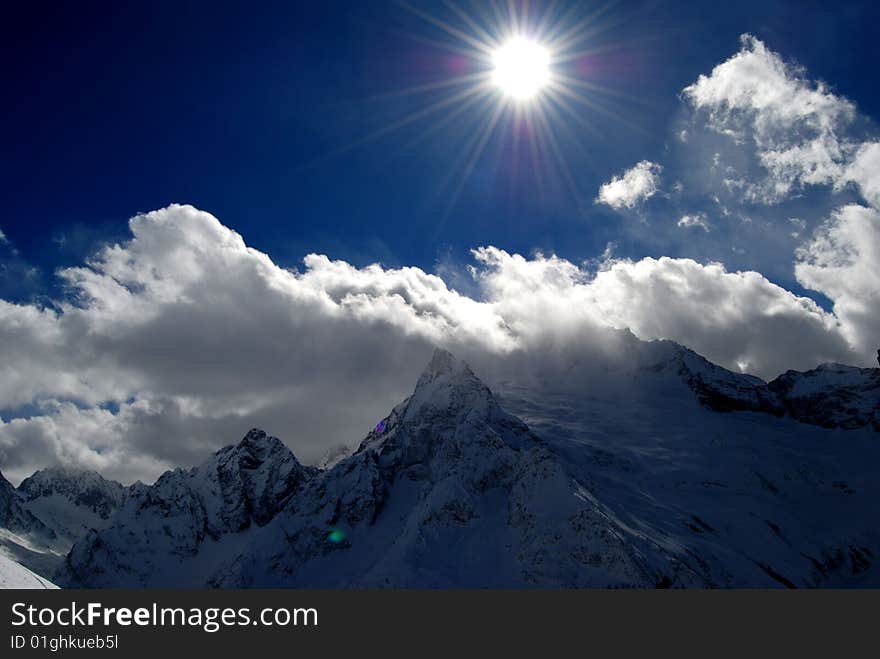 Snow covered high mountains under shining sun