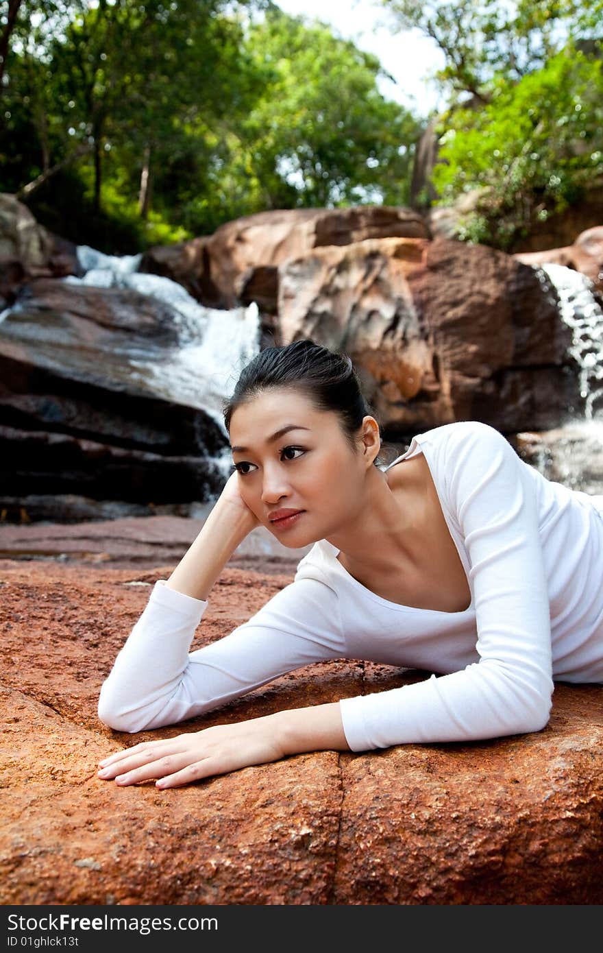 Young Woman Relaxing By The Waterfall