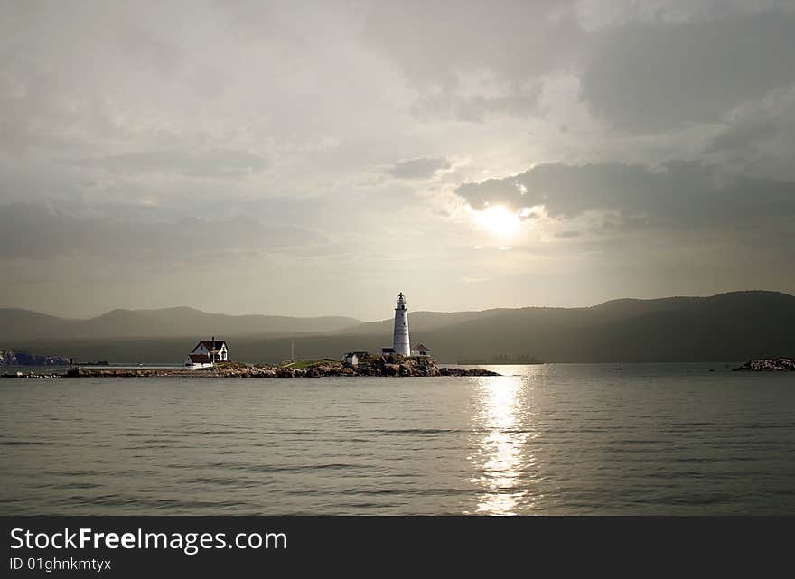 Lighthouse and house mountains in background sunset