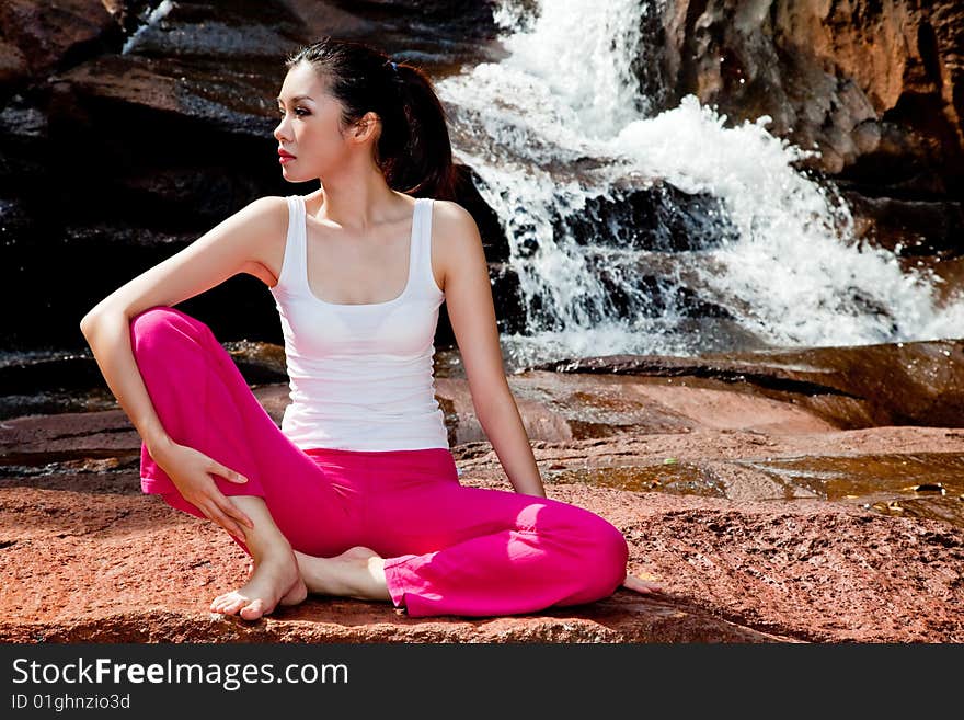 Outdoor waterfall young woman stretching her body. Outdoor waterfall young woman stretching her body