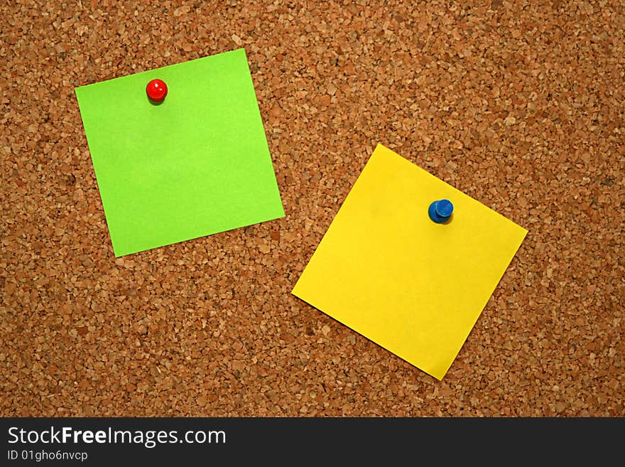 Green and yellow note in cork board. Green and yellow note in cork board