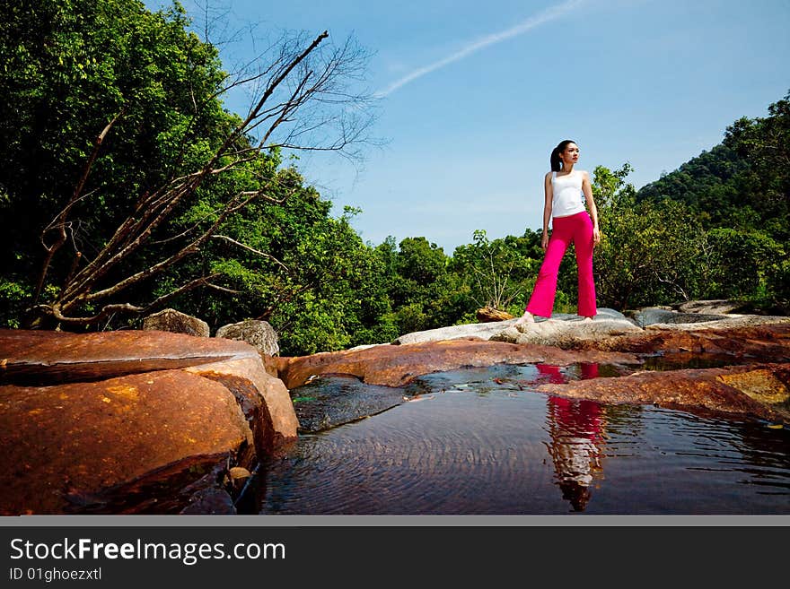 Young woman relaxing on the rock by the waterfall. Young woman relaxing on the rock by the waterfall