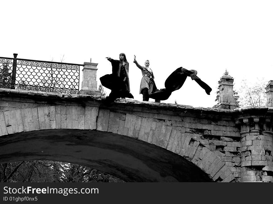 Two girls with flapping fabric in old bridge. Two girls with flapping fabric in old bridge