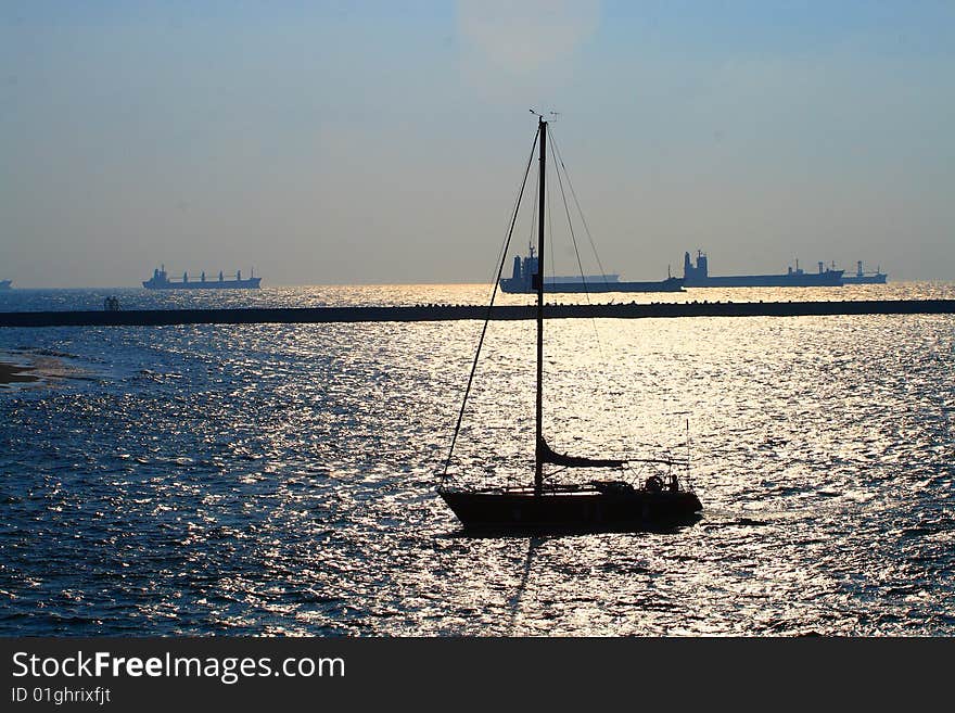 A sailboat arrving the port in the afternoon.