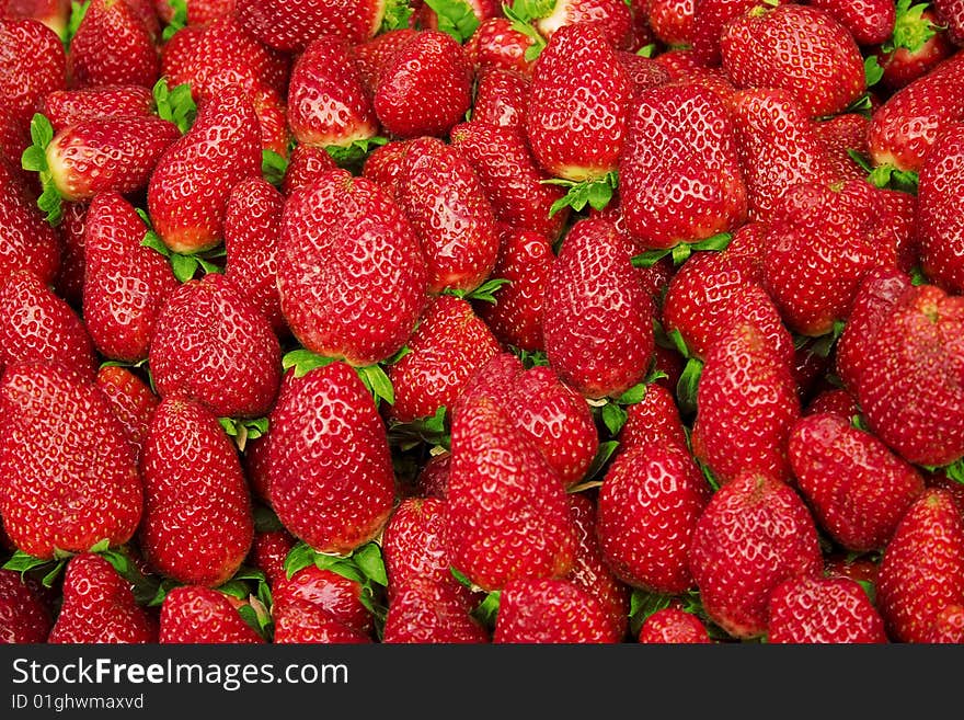 A lot of red strawberries with green leafs