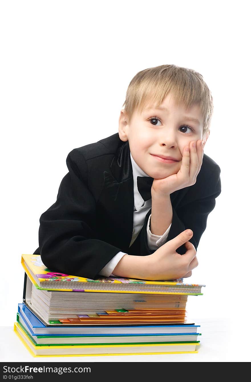 Bored schoolboy sitting by the table with a lot of books and unwilling to do homework