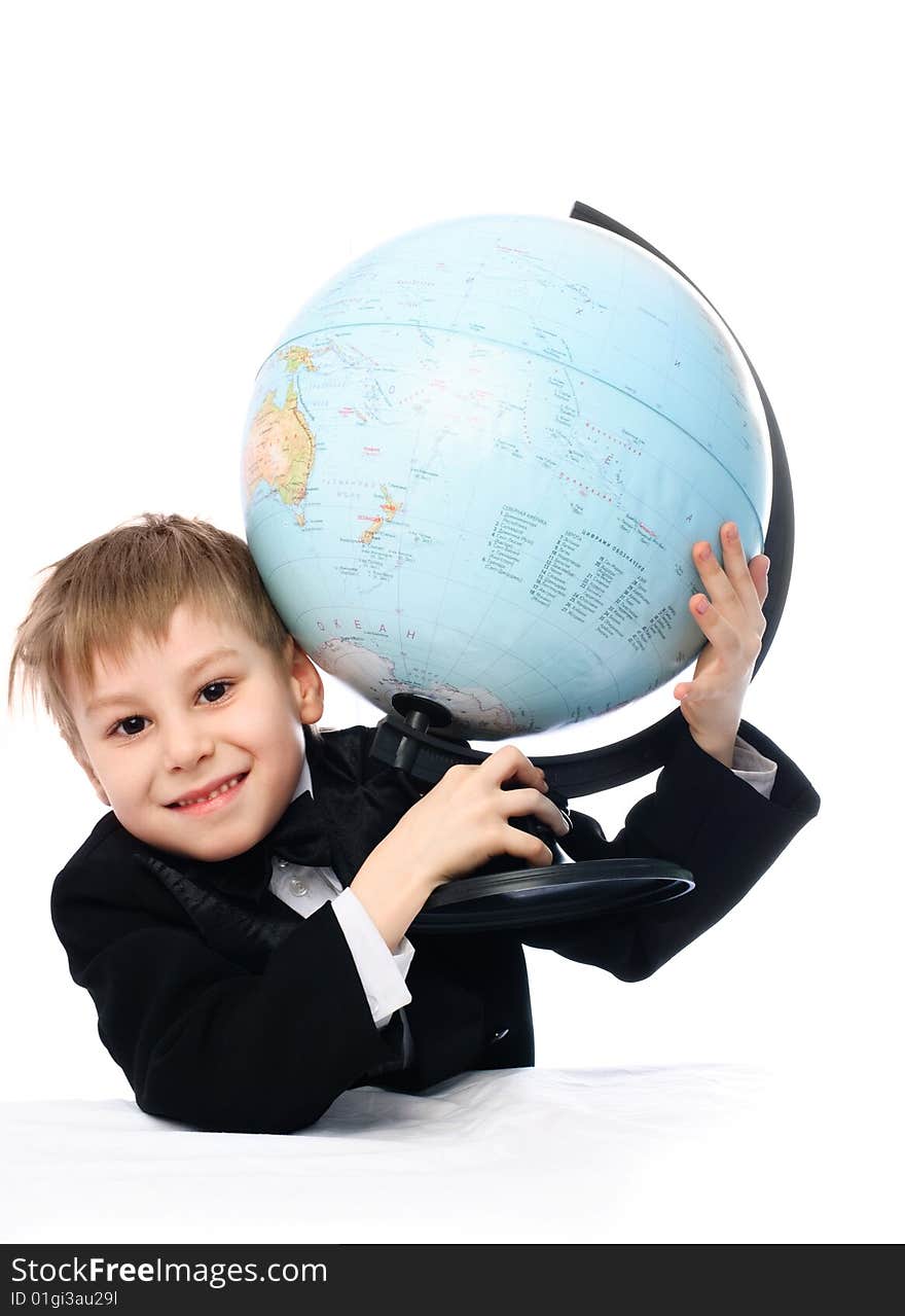 Happy schoolboy sitting by the table with a big globe in his hands. Happy schoolboy sitting by the table with a big globe in his hands