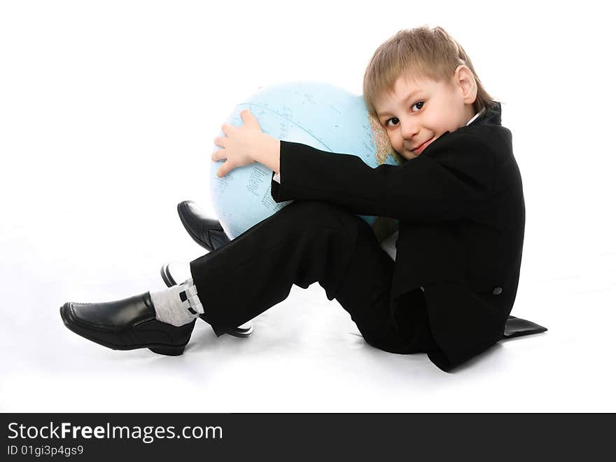 Happy little schoolboy sitting on the floor and embracing a big globe. Happy little schoolboy sitting on the floor and embracing a big globe