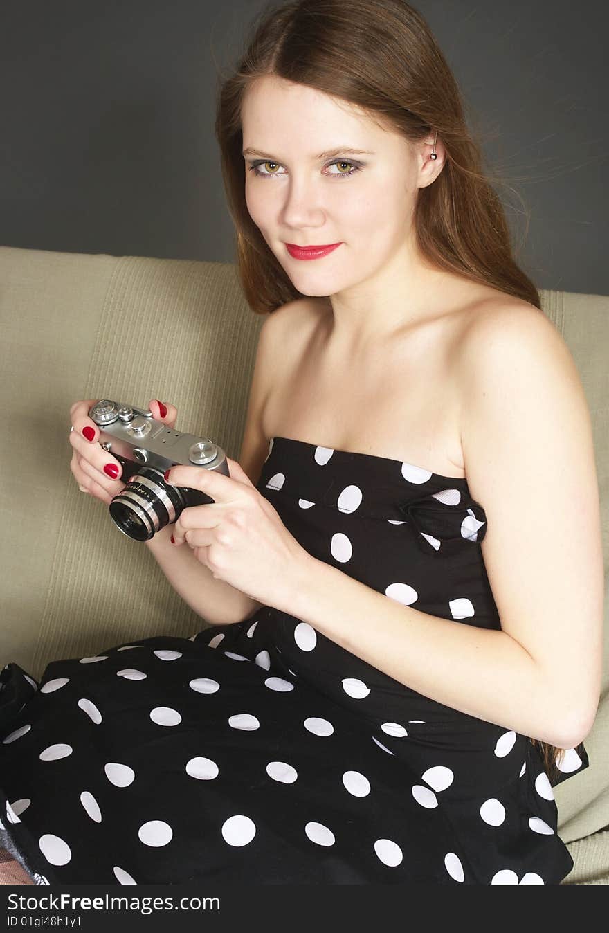 A young woman in vintage style clothes holding a retro camera. A young woman in vintage style clothes holding a retro camera.