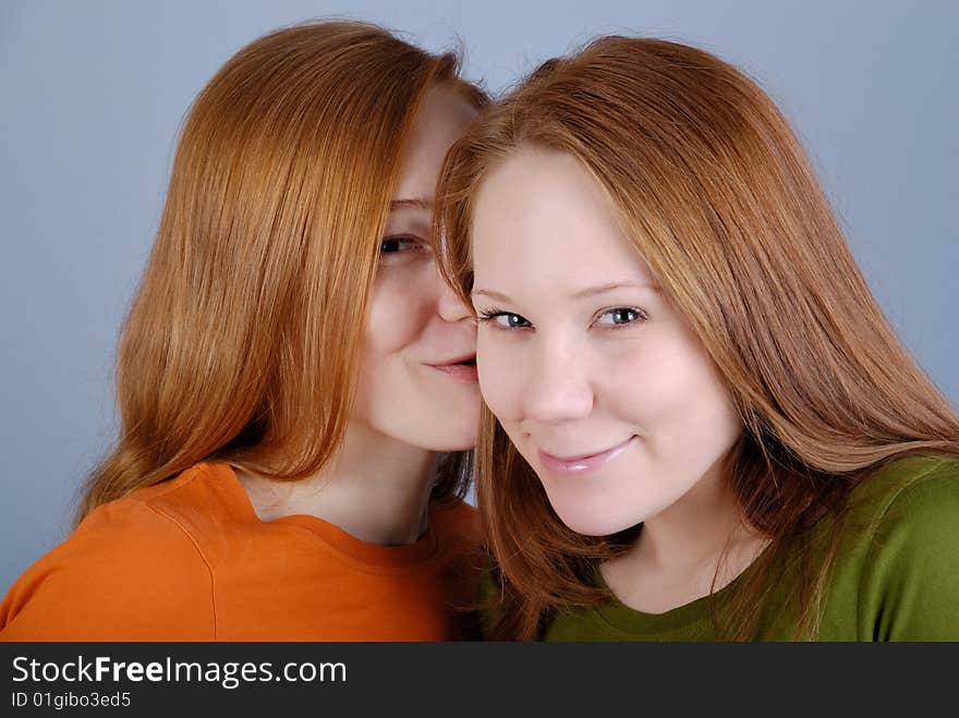 Two redhead young woman are secretive and smile. Two redhead young woman are secretive and smile