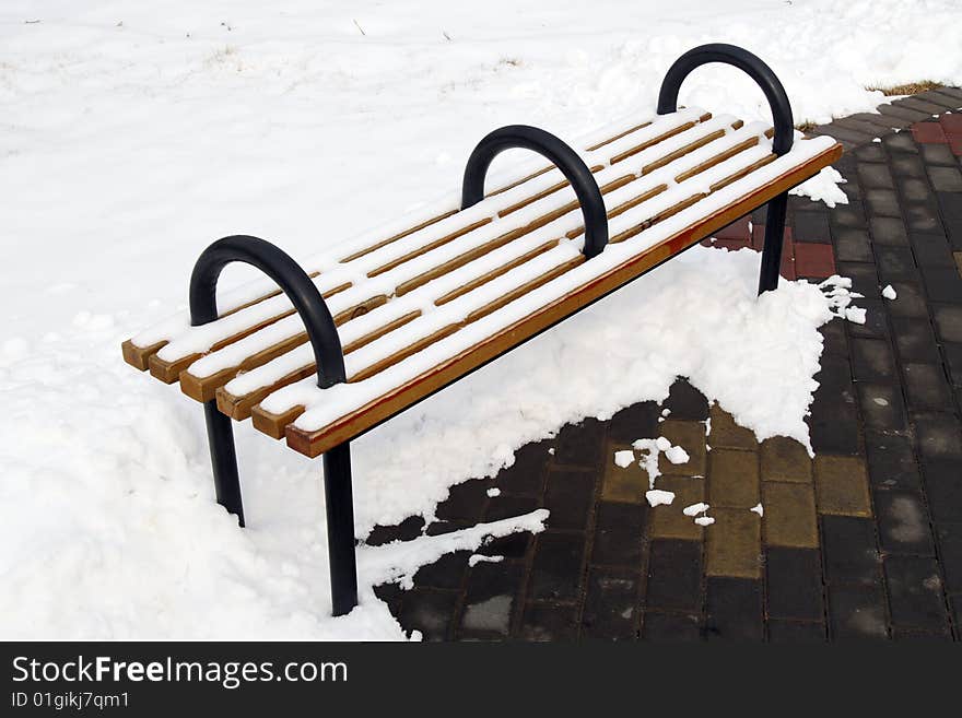 A bench on the snowfield in the park.