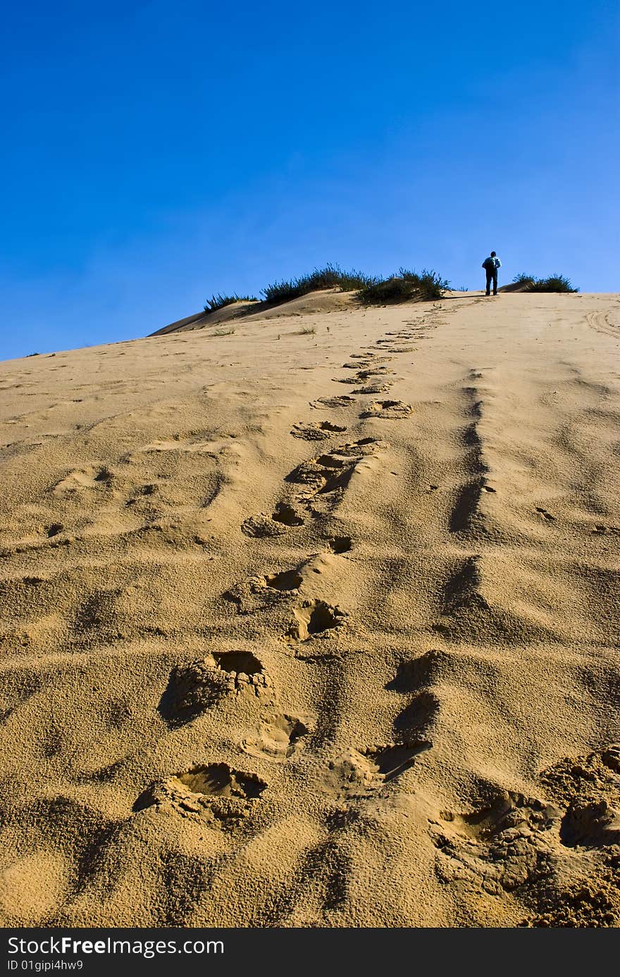 A man going up alone to the top of a sandy hill. A man going up alone to the top of a sandy hill.