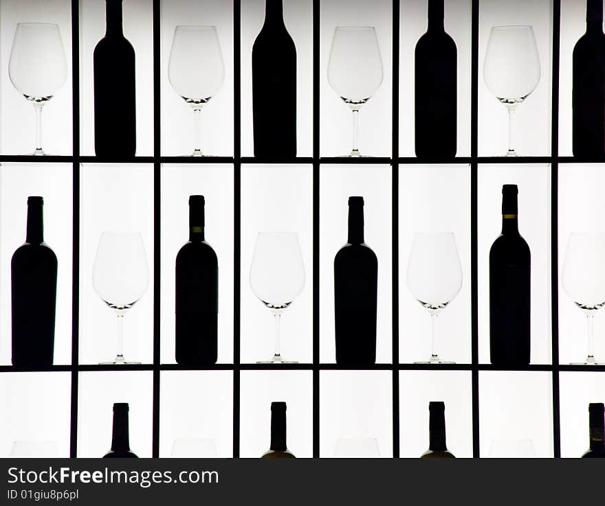 Black bottles and crystal glasses decorate a wall creating a motif