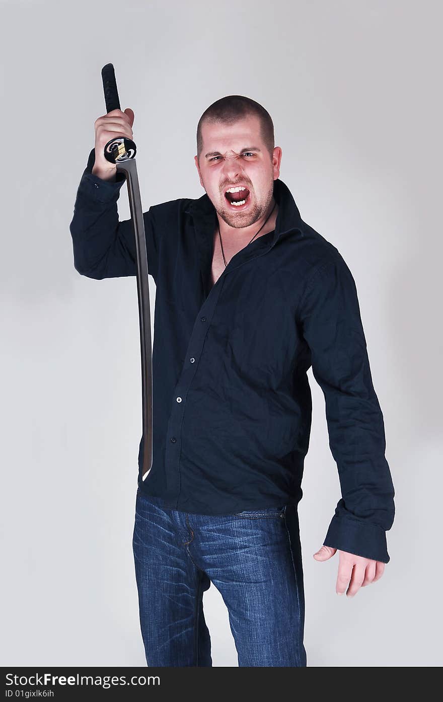 An very angry and dangerous young man wit a long sword screaming at the photographer, with light gray background. An very angry and dangerous young man wit a long sword screaming at the photographer, with light gray background.