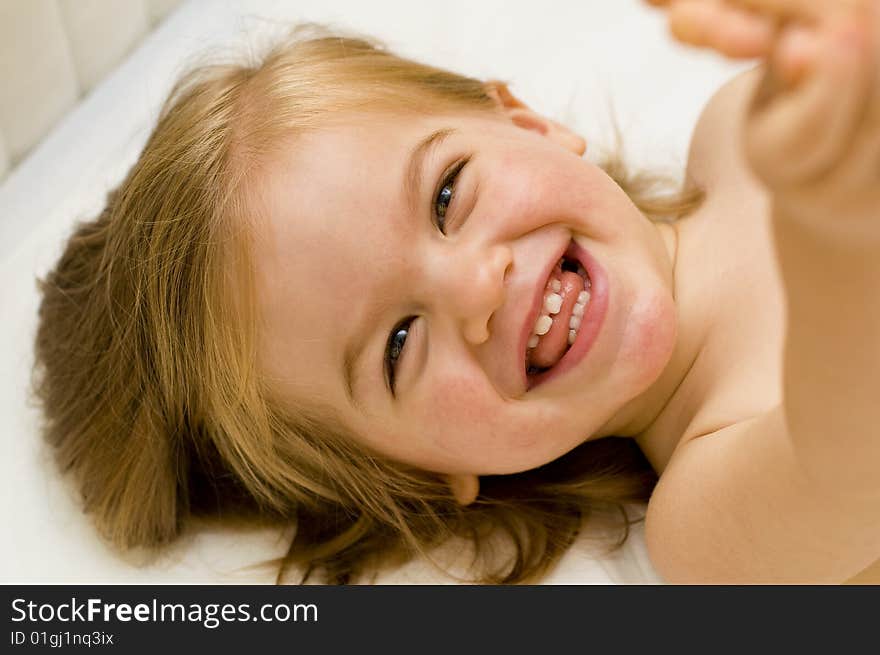 Beautiful baby girl smiling and laughing in her cot just before bedtime