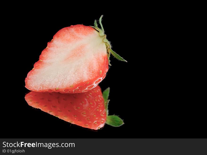 Half strawberry isolated on black with reflection