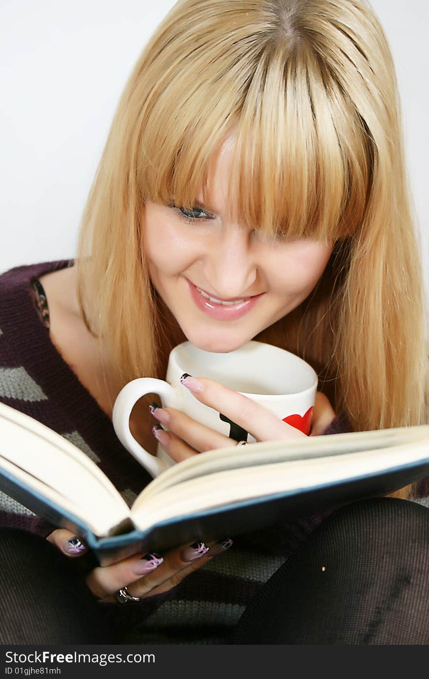 Portrait of a  young lady reading book with  cup in hand. Portrait of a  young lady reading book with  cup in hand