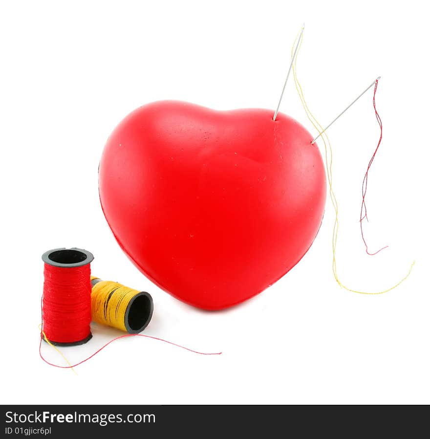 Heart shaped pincushion with spools and needles isolated on a white background