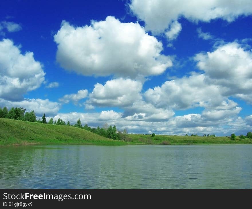 Pond and white clouds on blue sky