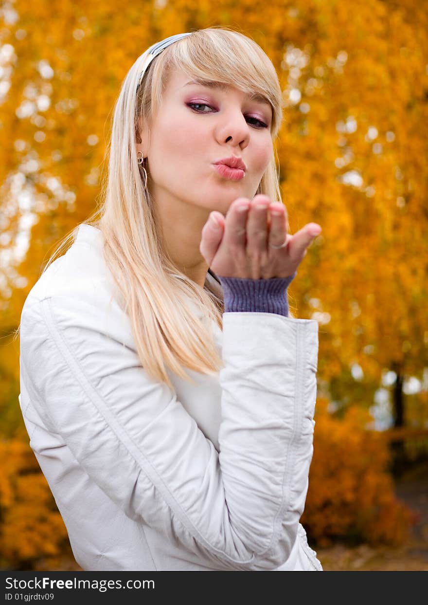 Pretty girl throwing a kiss - autumn park background - shallow DOF