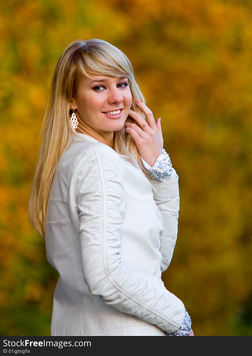 Pretty girl adjusting her hair on autumn park background - shallow DOF