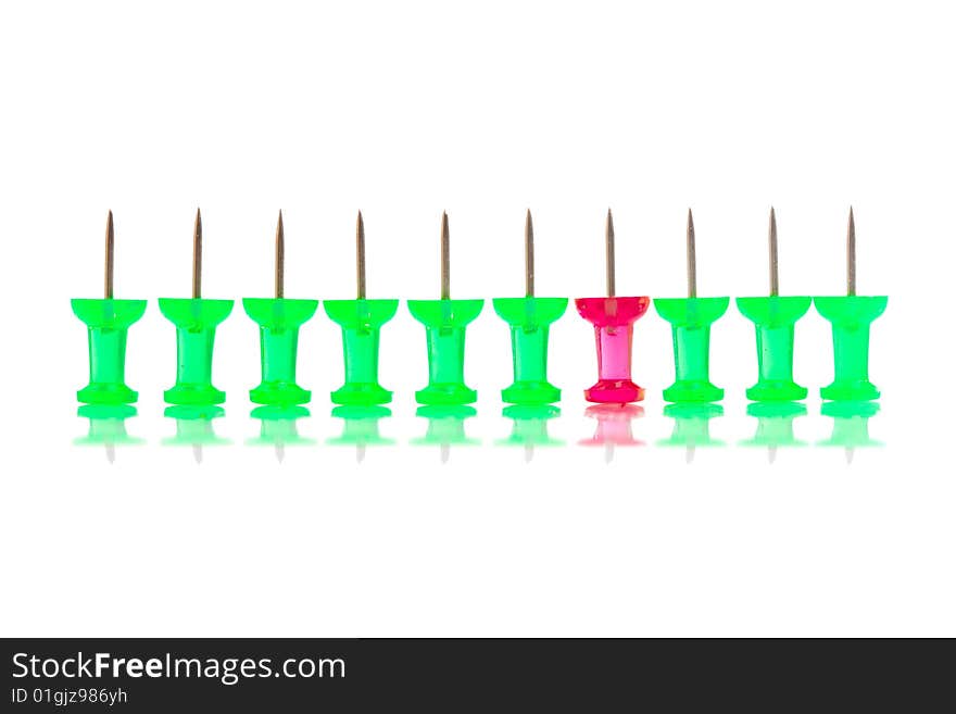 A red push pin stands in a row of green ones. A red push pin stands in a row of green ones