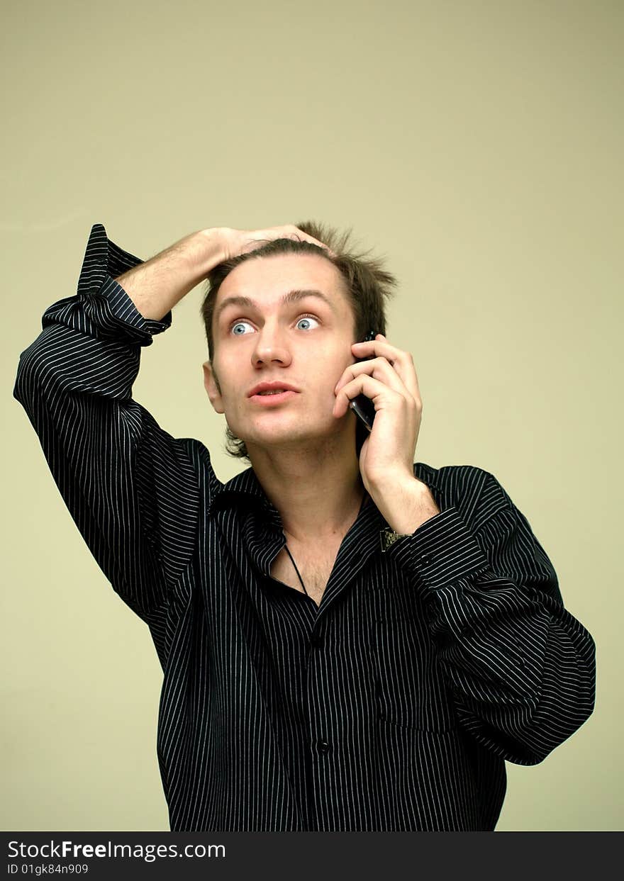 Young man in stressful condition is talking on the phone, grab hand on your head. Young man in stressful condition is talking on the phone, grab hand on your head