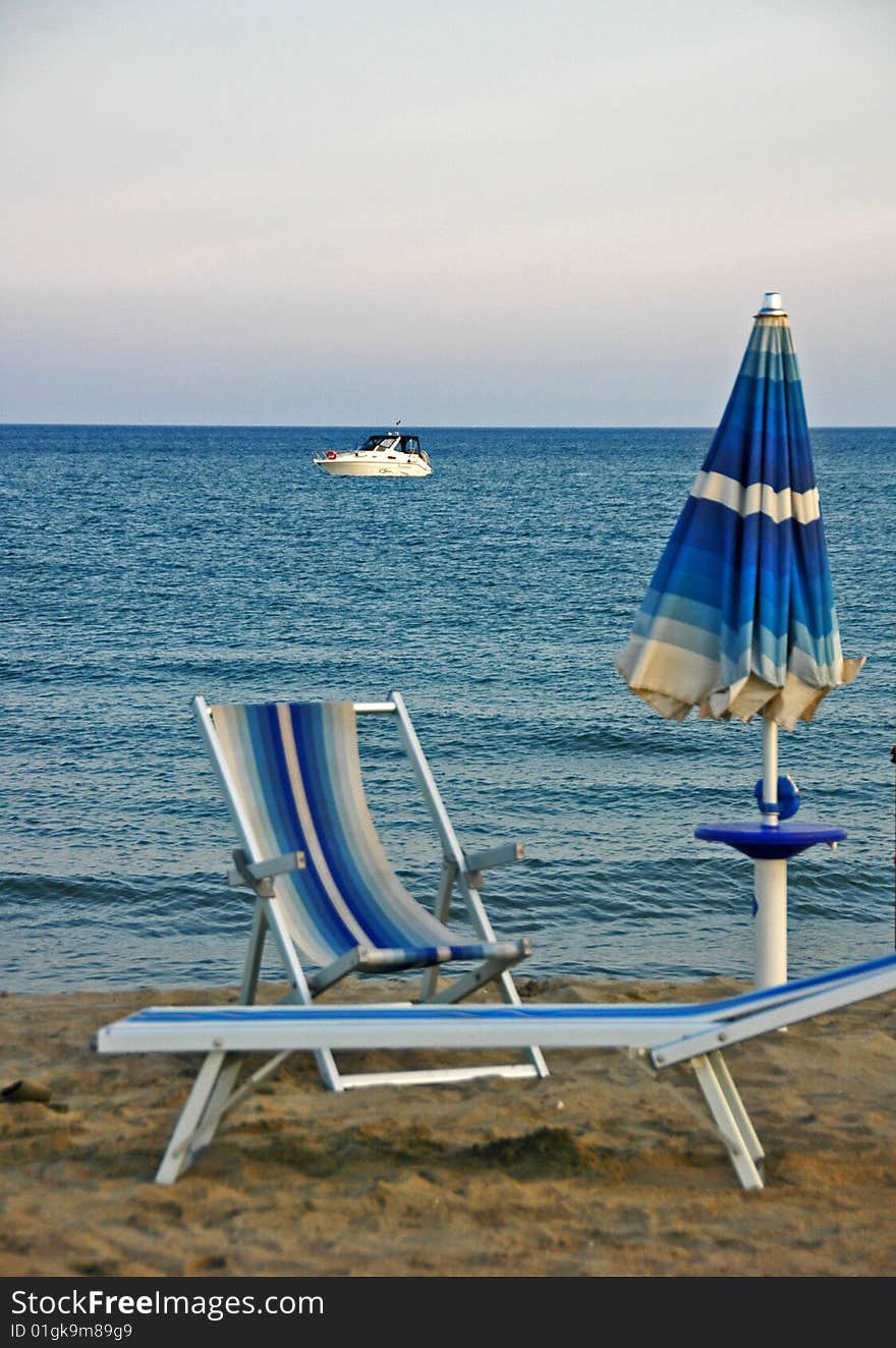 Desert beach at sunset with umbrella and bed